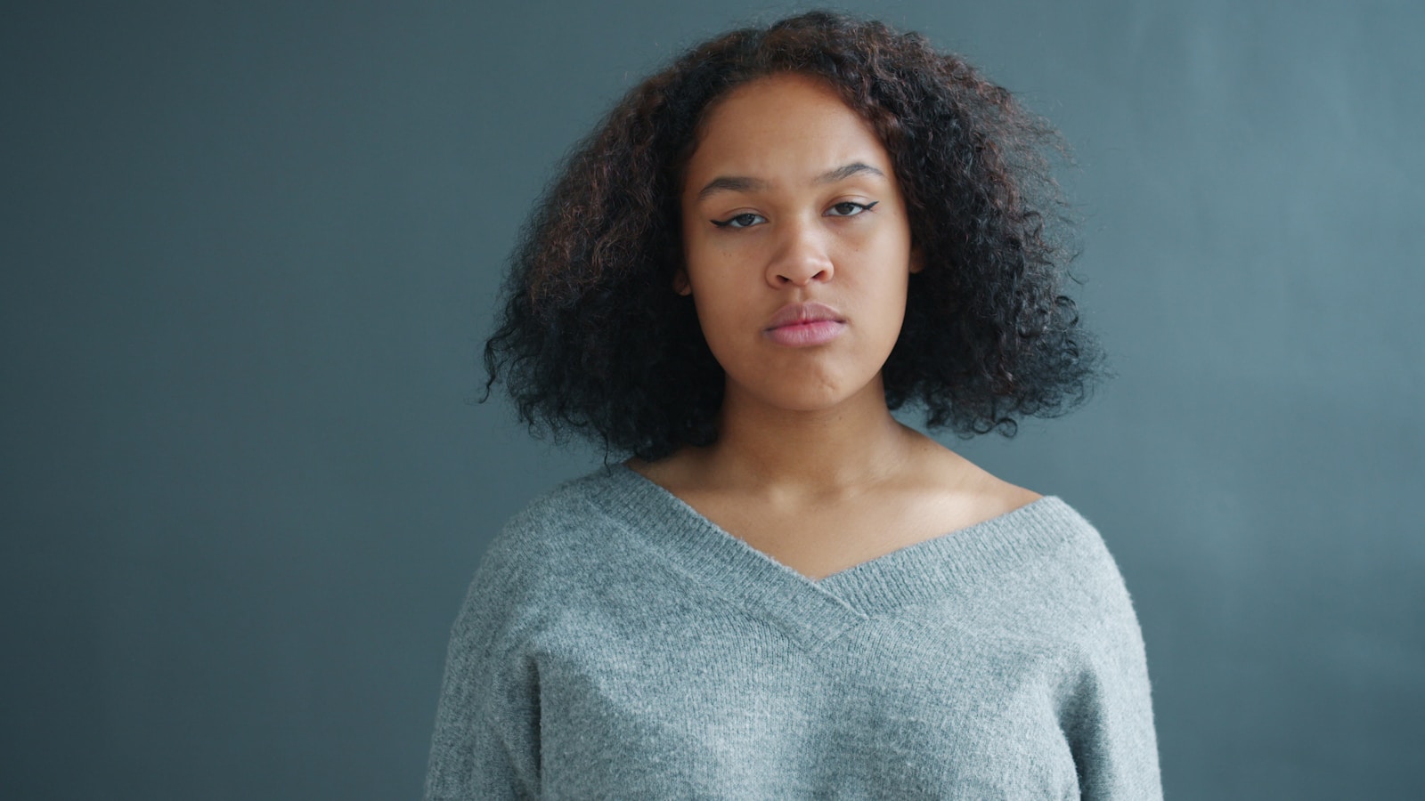 Young woman with curly hair against a gray background.